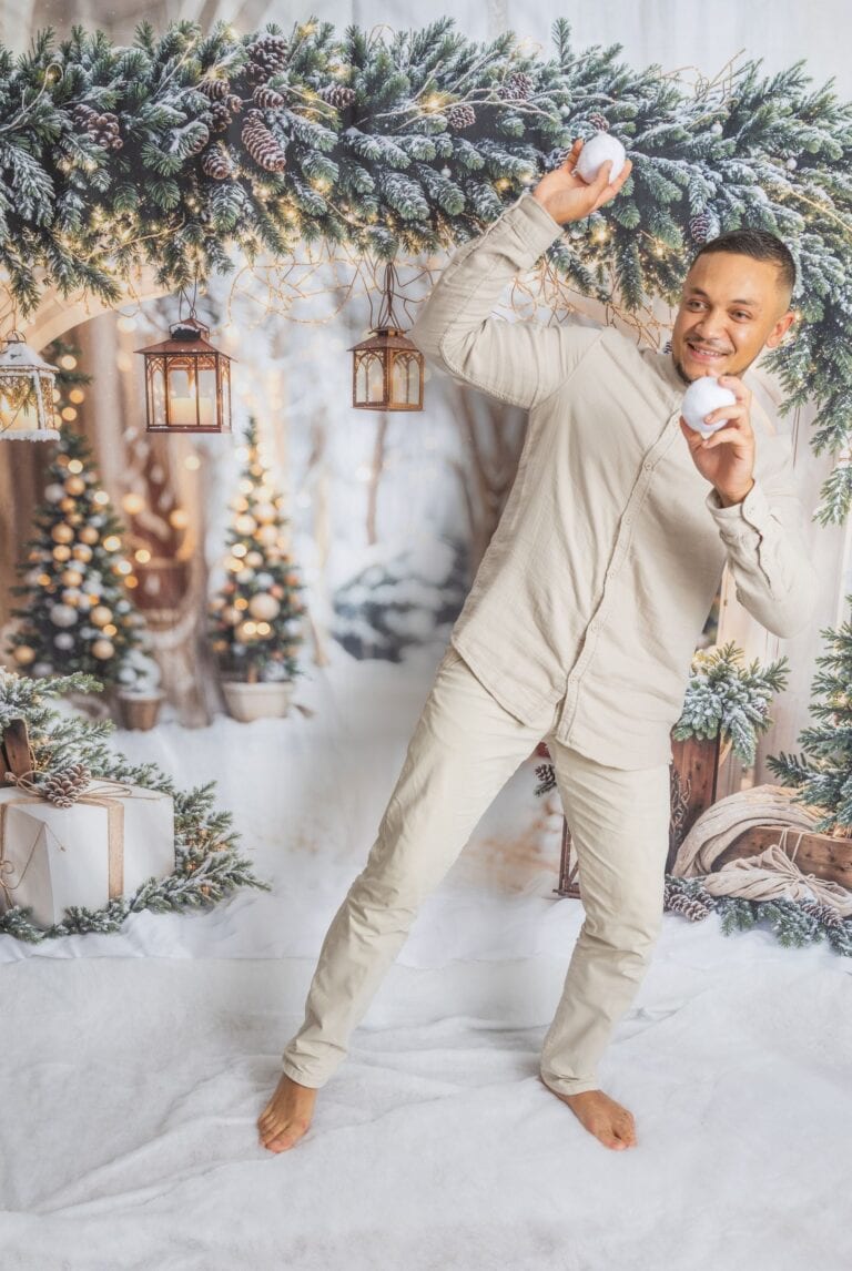 Homme souriant tenant des boules de neige décor Noël