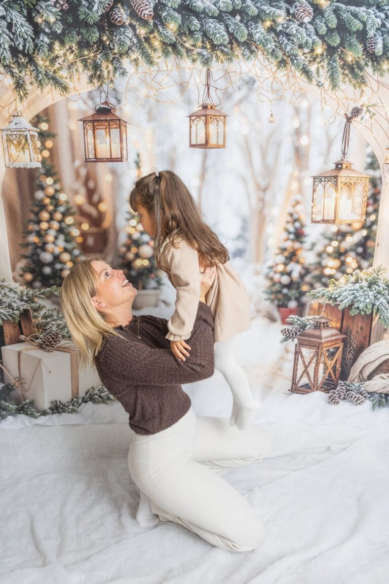 Enfant et mère jouent sous un sapin de Noël décoré, ambiance chaleureuse et festive.