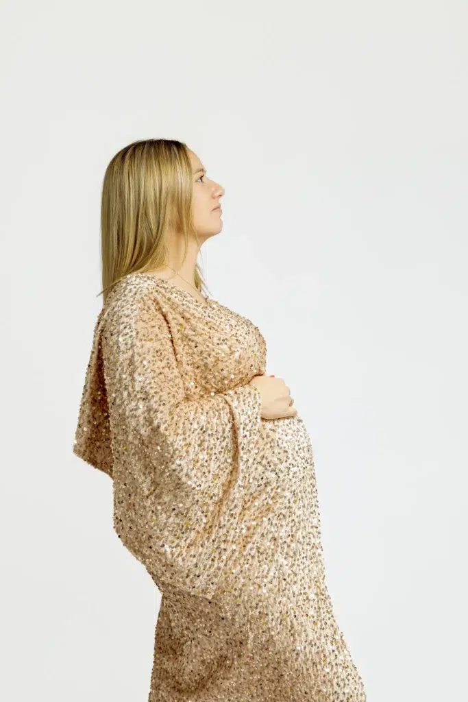 Femme enceinte en robe dorée à sequins, vue de profil