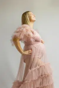 Femme enceinte souriante en robe rose de tulle