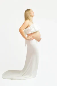 Femme enceinte en robe blanche, mains sur le ventre