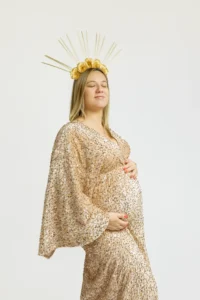 Femme enceinte en robe dorée et couronne florale