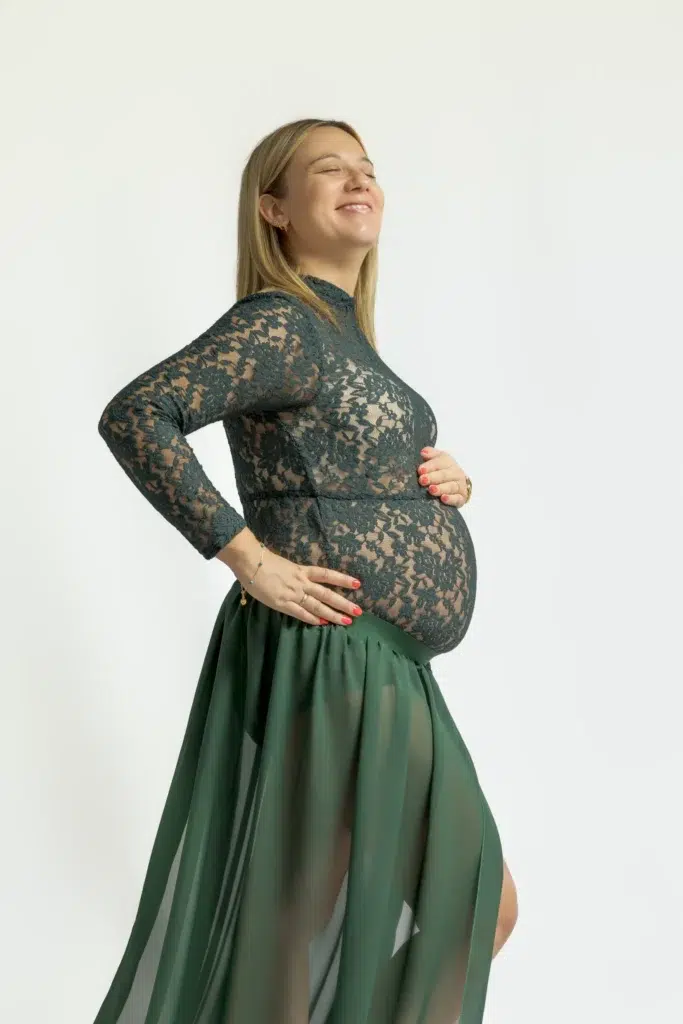 Femme enceinte souriante en robe verte en dentelle