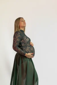 Femme enceinte en robe verte, mains sur le ventre
