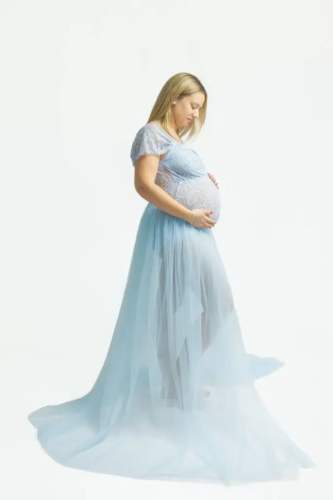 Femme enceinte en robe bleue caressant son ventre