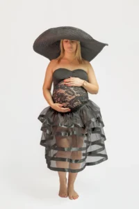 Femme enceinte en robe noire et chapeau XXL