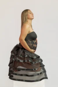 Femme enceinte en robe noire posant de profil