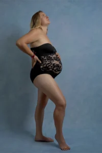 Femme enceinte posant en lingerie noire sur fond bleu