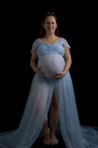 Femme enceinte souriante en robe bleue sur fond noir