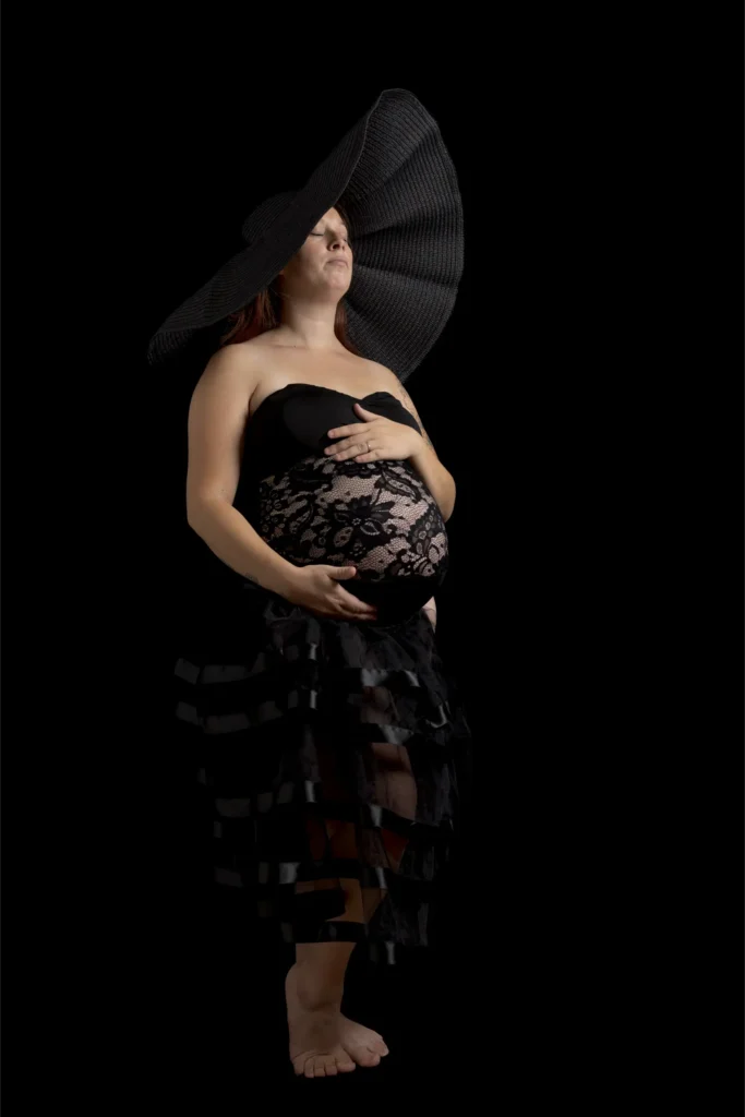 Femme enceinte en robe noire et grand chapeau