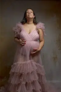 Femme enceinte en robe rose, yeux fermés
