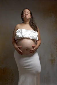 Femme enceinte en tenue blanche, mains sur le ventre
