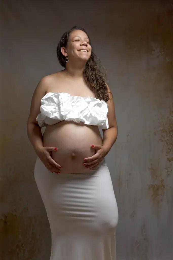 Femme enceinte souriante en tenue blanche – séance grossesse en studio à Ancenis