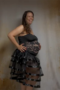 Femme enceinte souriante en robe noire à volants