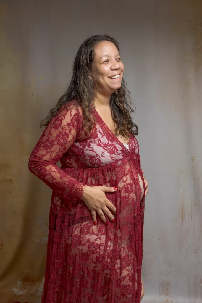 Femme enceinte souriante en robe bordeaux en dentelle – séance grossesse en studio à Ancenis