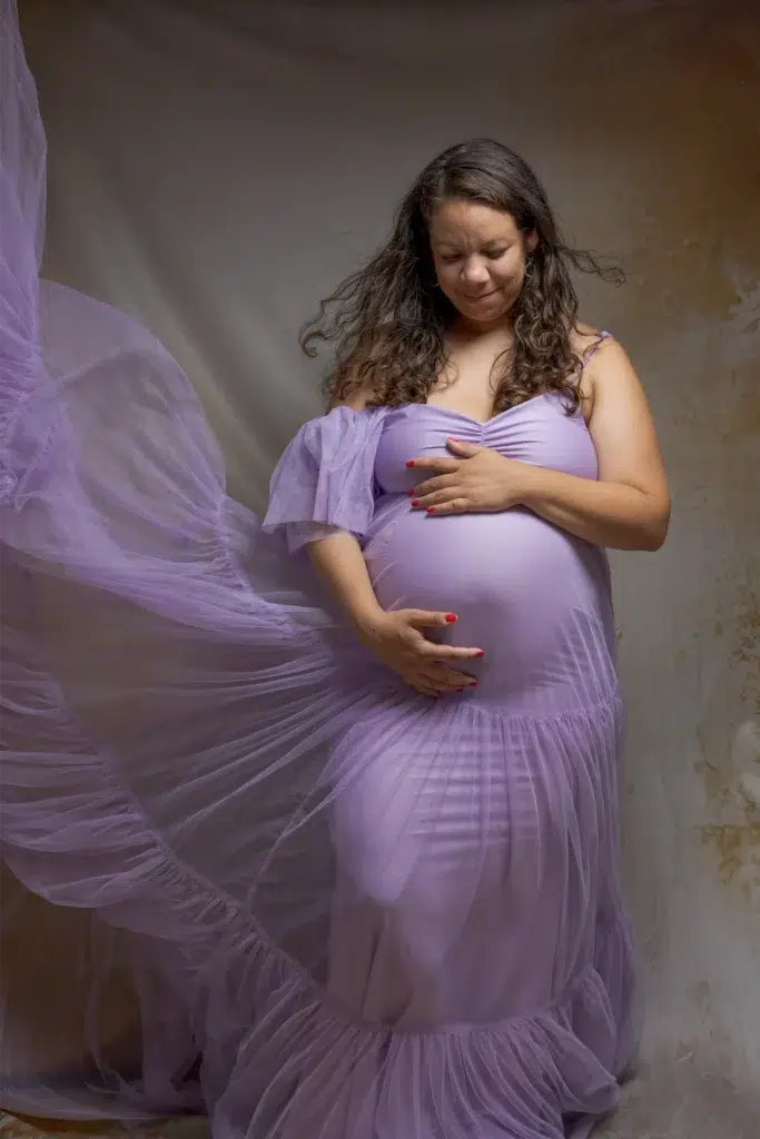 Femme enceinte en robe lavande, mains sur le ventre – séance grossesse en studio à Ancenis