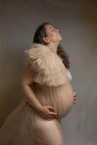 Femme enceinte souriante en robe de tulle beige