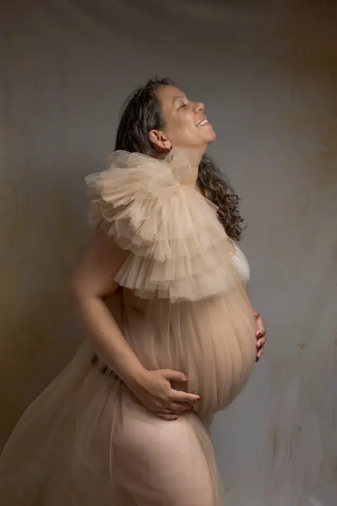 Femme enceinte souriante en robe de tulle beige