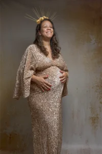 Femme enceinte souriante en robe dorée à sequins