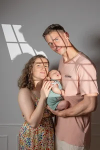 Parents souriants tenant leur bébé devant une fenêtre